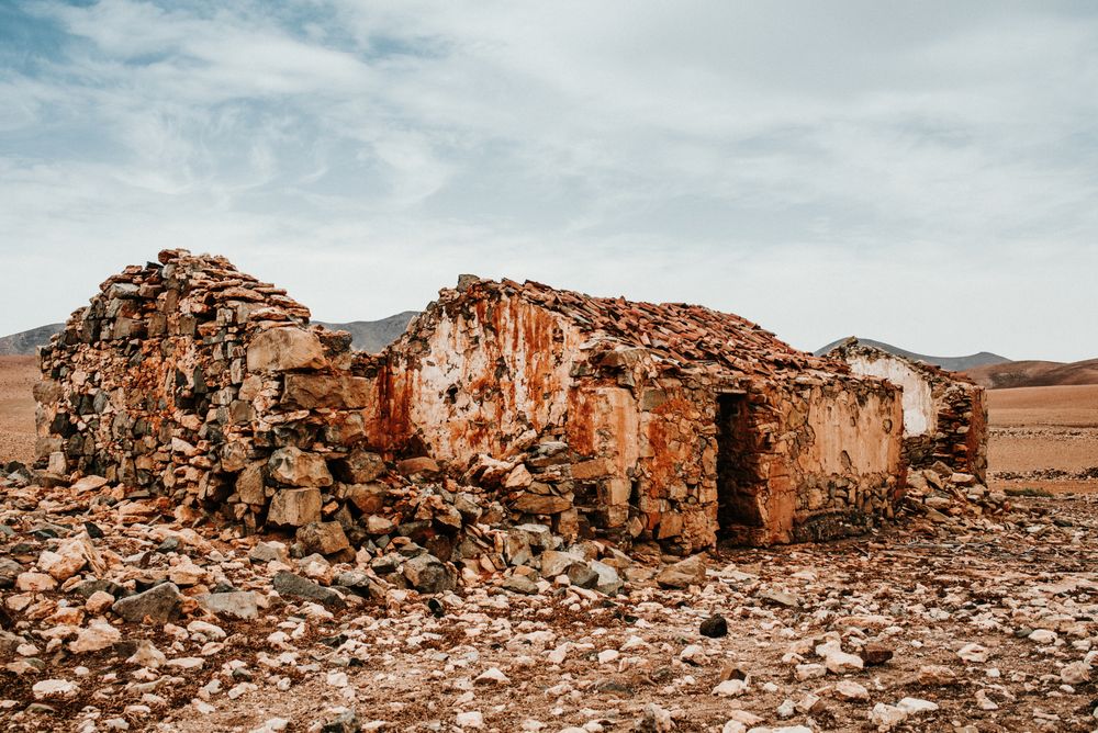 Dilapidated old buildings in mountain desert under cloudy sky