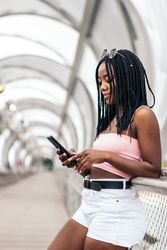 Portrait of a Black young woman enjoying the summer in the city using smartphone