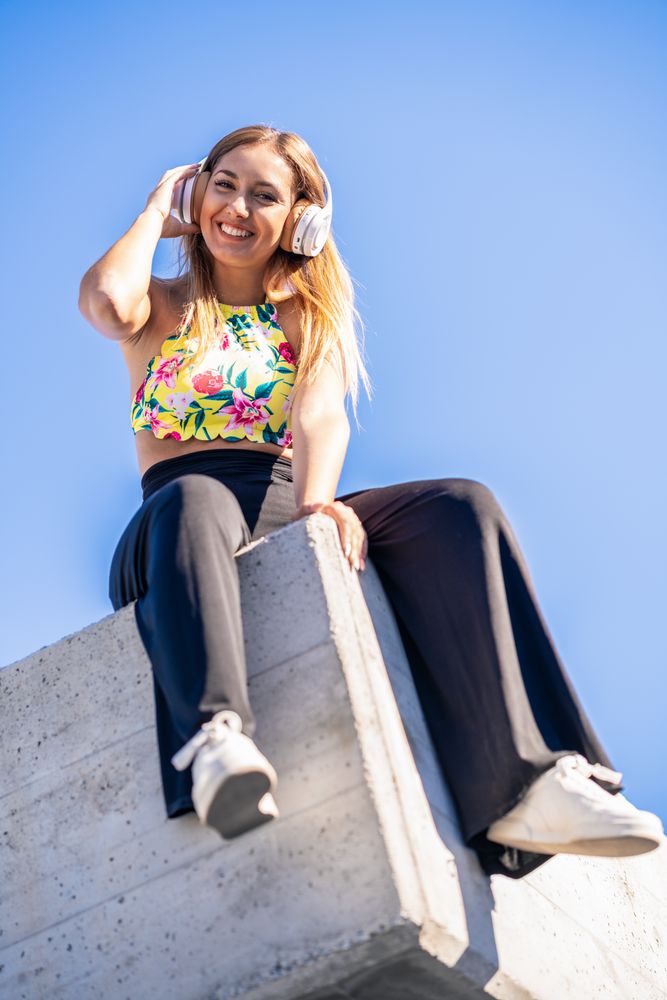 Woman sitting on corner of building roof listening to music