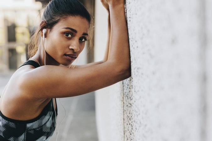 Female athlete exercising outdoors with forearms to a wall