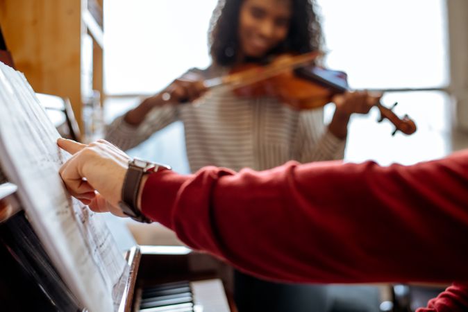 Man playing piano near woman playing violin in studio