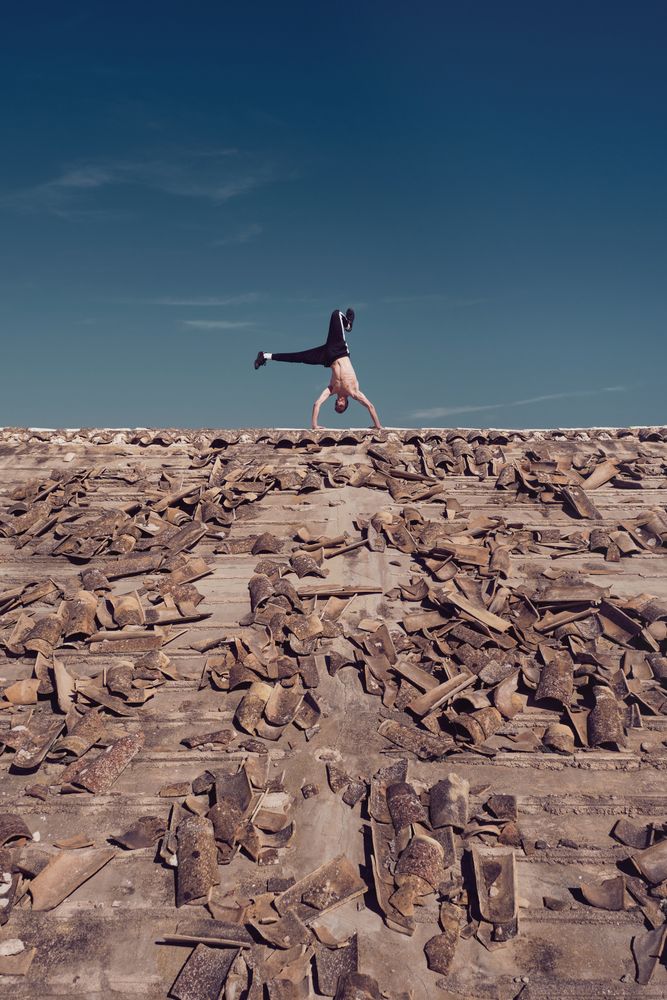 Man dancing breakdance on roof on building