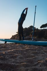 Man practicing paddle surfing with neoprene in a sunrise