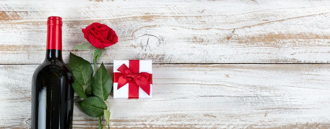Valentine’s Day celebration with red wine and gifts rose on rustic wooden background