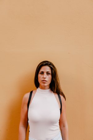 Young brunette standing against orange background