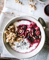 Delicious breakfast bowl with quinoa, rice and groats near tea cup and newspaper