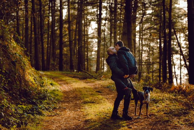 Men hugging and kissing on countryside road near dog