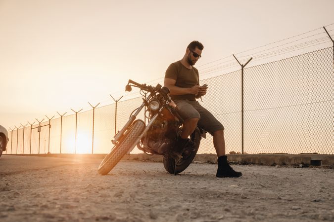 Man sitting on motorcycle and surfing mobile