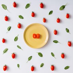 Yellow plate with halved tomato on tomato and basil pattern on light background