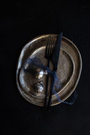 Minimal Christmas table setting with ceramic plate and silver ornaments