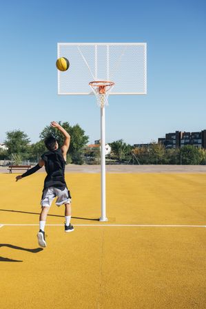 Young man playing on basketball court outdoor.