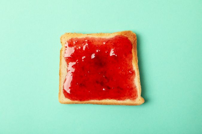 Toast with strawberry jam on mint background, top view
