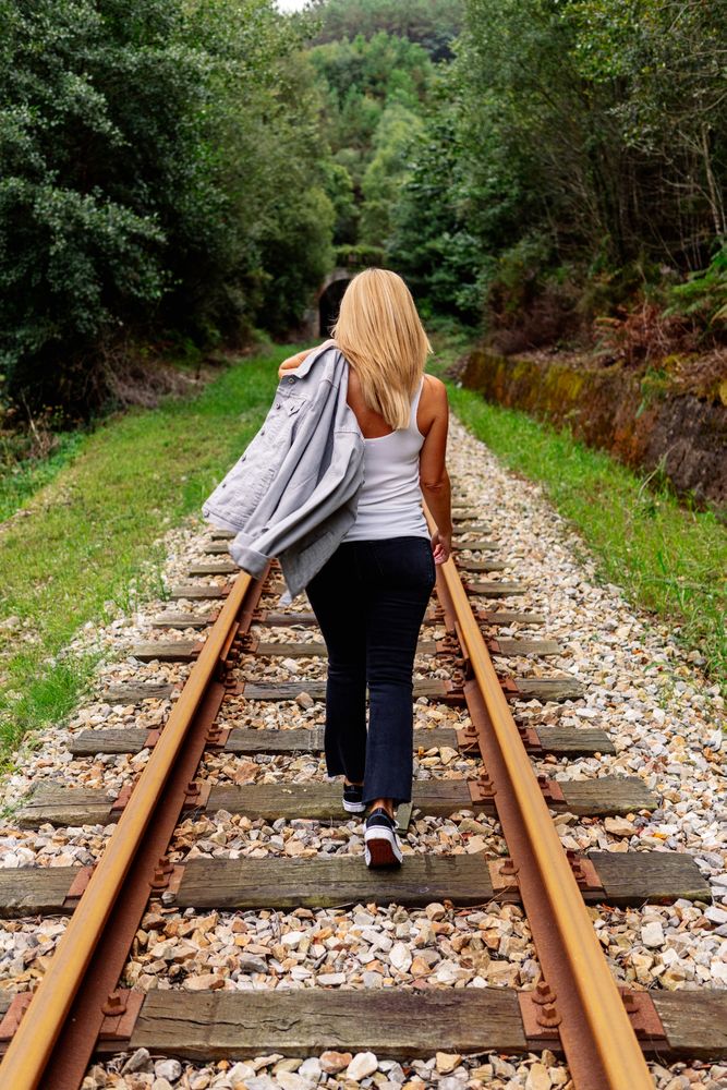 Woman walking along railway though greenery part of road