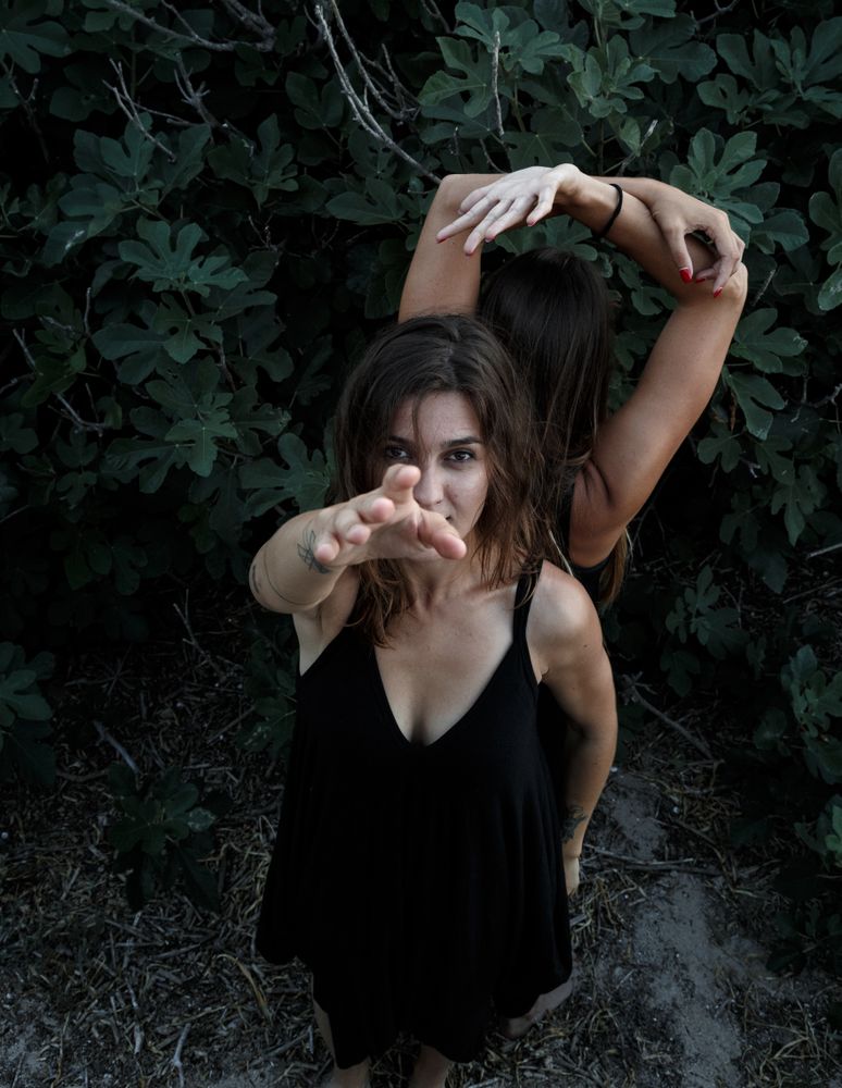 Young women posing near green bush