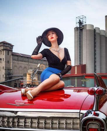 Retro red Cadillac with a woman sitting on the hood