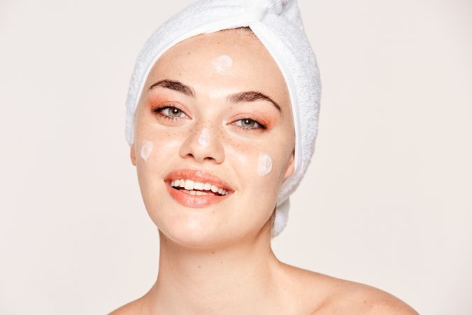 Delighted female with radiant skin applying cream