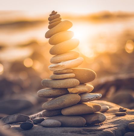 A stack of gray stones on beach during sunset