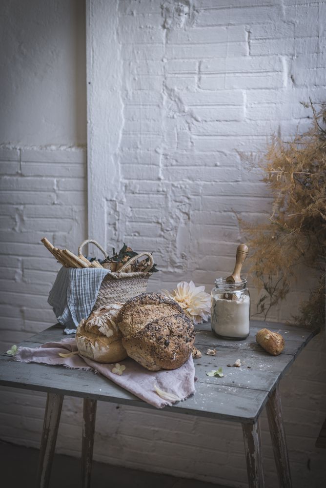 Fresh bread on served table and bunch of dry plant hanging on thread