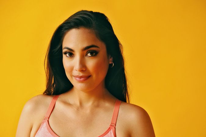 Headshot of calm Hispanic woman standing in front of a yellow background