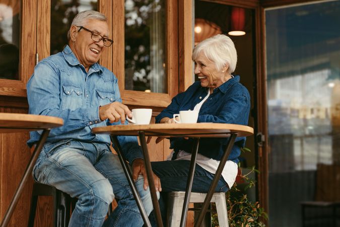 Older couple having conversation while drinking coffee together in cafe