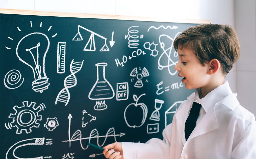 Side view of boy drawing on chalkboard