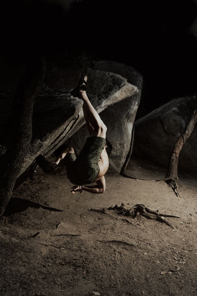 Man practicing rock climbing among large rocks in a forest