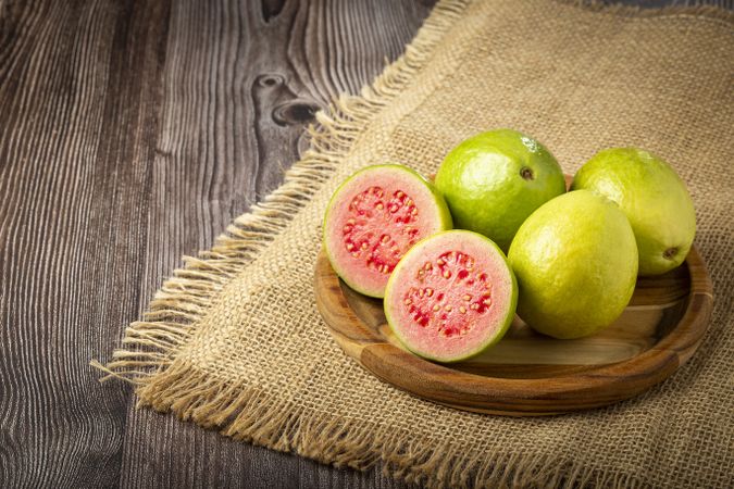Fresh sliced guavas on wooden table.