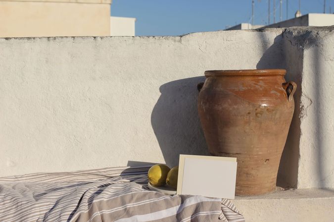 Summer vacation still life. Blank horizontal greeting card, invitation mock up in sunlight. Vintage olive clay pot and fresh lemons fruit