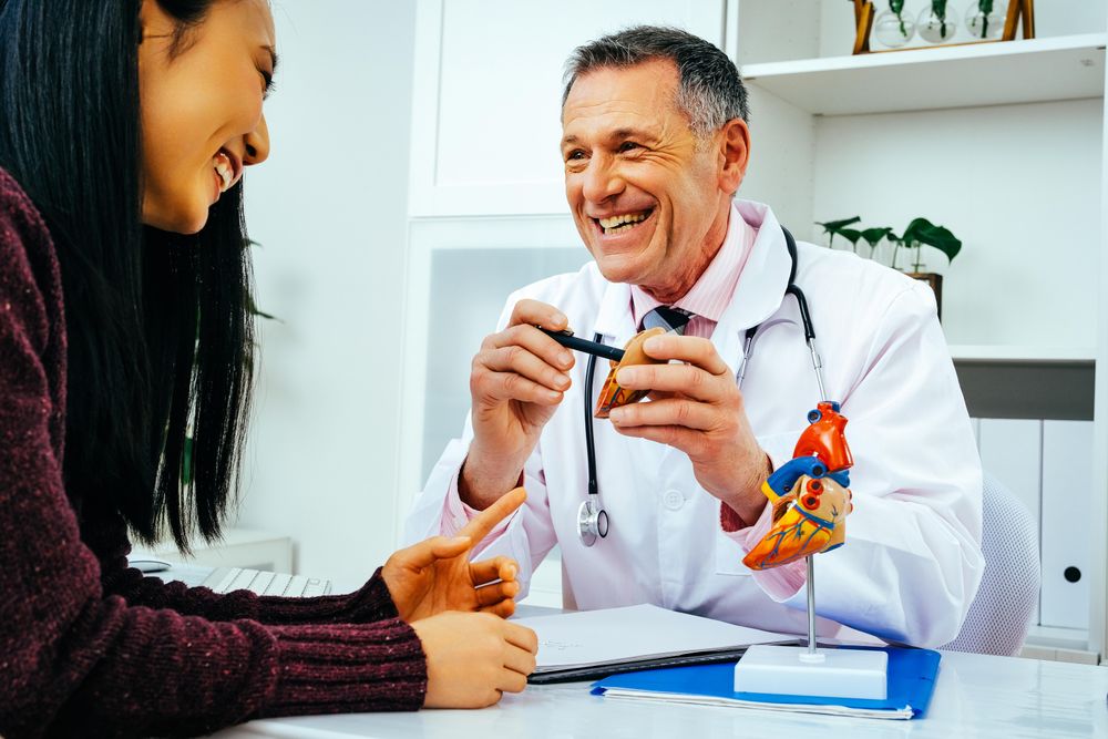 Happy male doctor with female patient consulting about heart structure