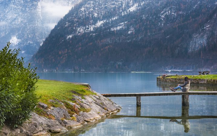 Woman sitting on a bridge over Hallstatter Lake in Austria