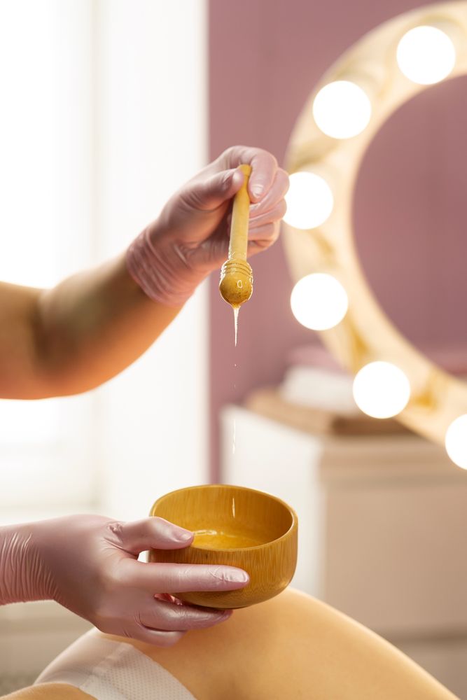 Honey slowly dripping from wooden stick during spa session.
