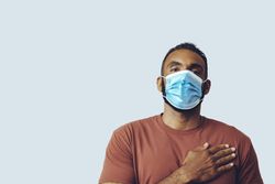 Male wearing medical face mask with hand on chest in studio shoot
