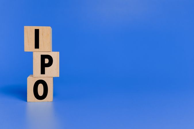 IPO letter text or initial public offering words on wooden blocks isolated on blue background copy space