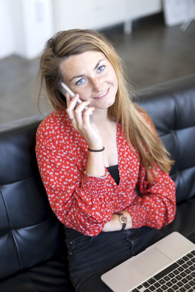 Woman talking on the phone sitting on a sofa in living room at home