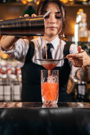 Female bartender preparing a cocktail in a traditional cocktail bar