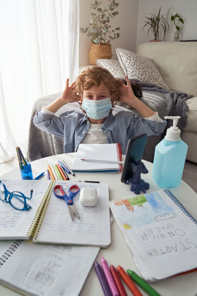 Little child wearing mask while studying at home