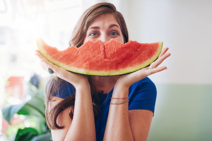 Young woman holding watermelon slice shaped like a smile