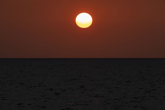 Sunset turns the sky orange over the horizon, seen from Pulau Poya, Indonesia