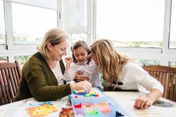 Woman playing board game with daughter and granddaughter