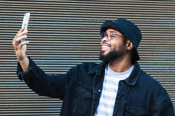 Laughing Black man taking selfie on smartphone