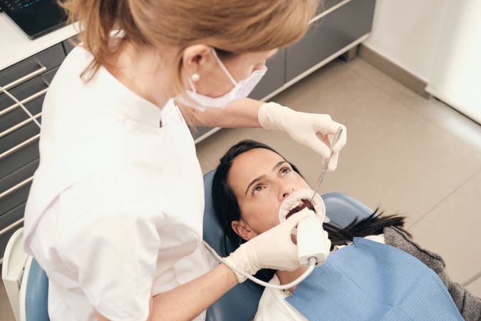 Unrecognizable dentist making teeth scan to woman