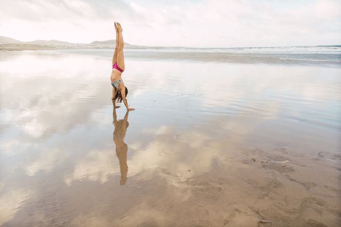 Woman doing handstand near sea