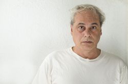 Portrait of surprised middle aged man in light shirt against light wall