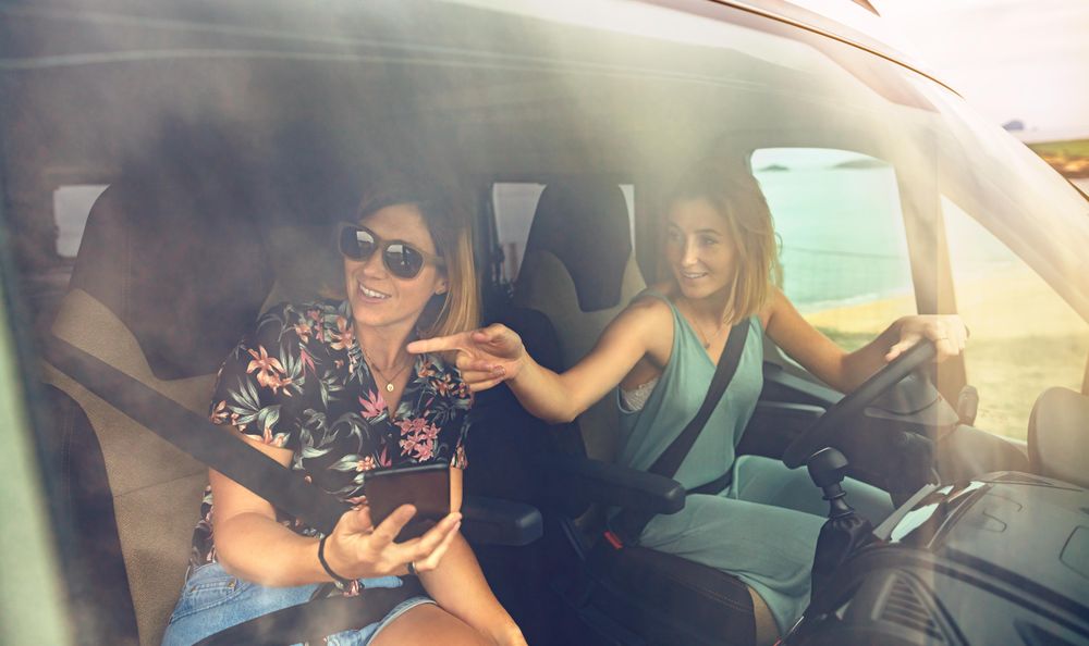 Woman pointing outside while driving a motorhome with her female friend in passenger seat