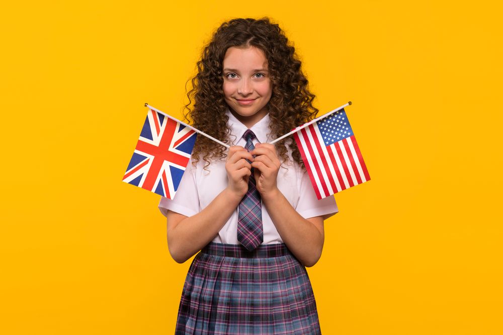 Smiling girl holding USA and UK flags