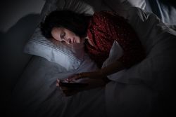 woman scrolling smartphone in darkness