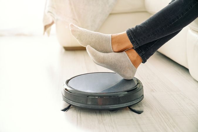 Woman placing hands on robotic vacuum cleaner