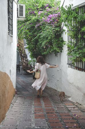 Woman walking downstairs with dog on narrow street