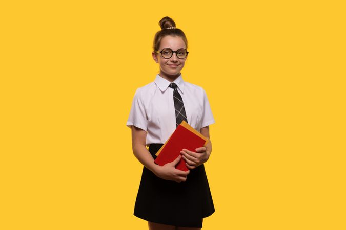 Teen girl holding books, wearing glasses and school uniform