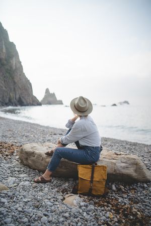 Woman resting on beach stone by sea
